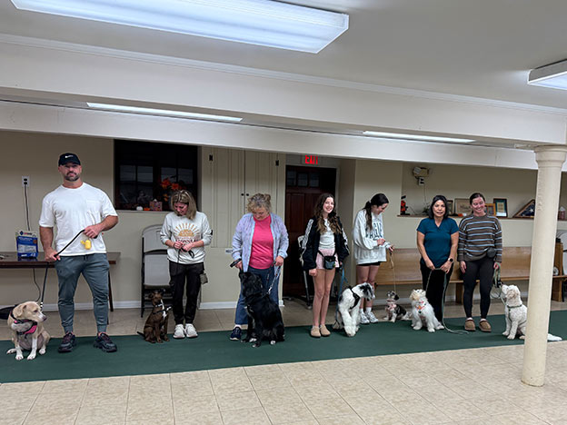 Proud dog owners with their pets at a training class graduation ceremony