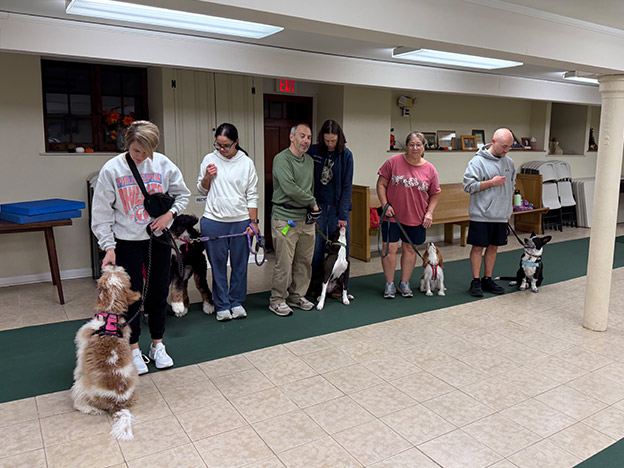 Proud dog owners with their pets at a training class graduation ceremony