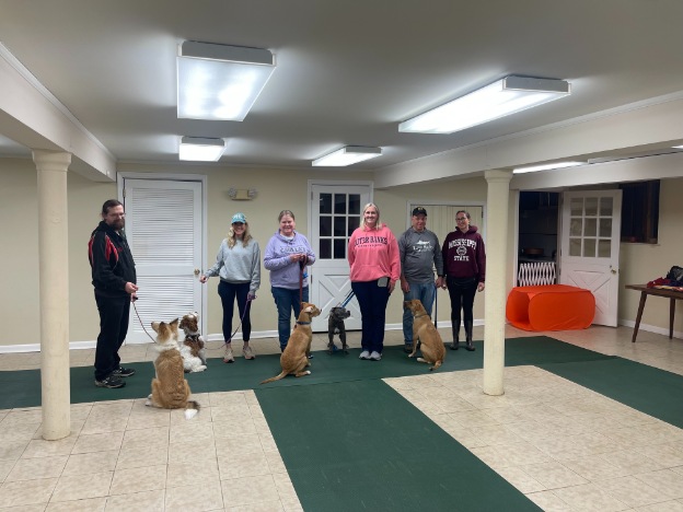 Proud dog owners with their pets at a training class graduation ceremony